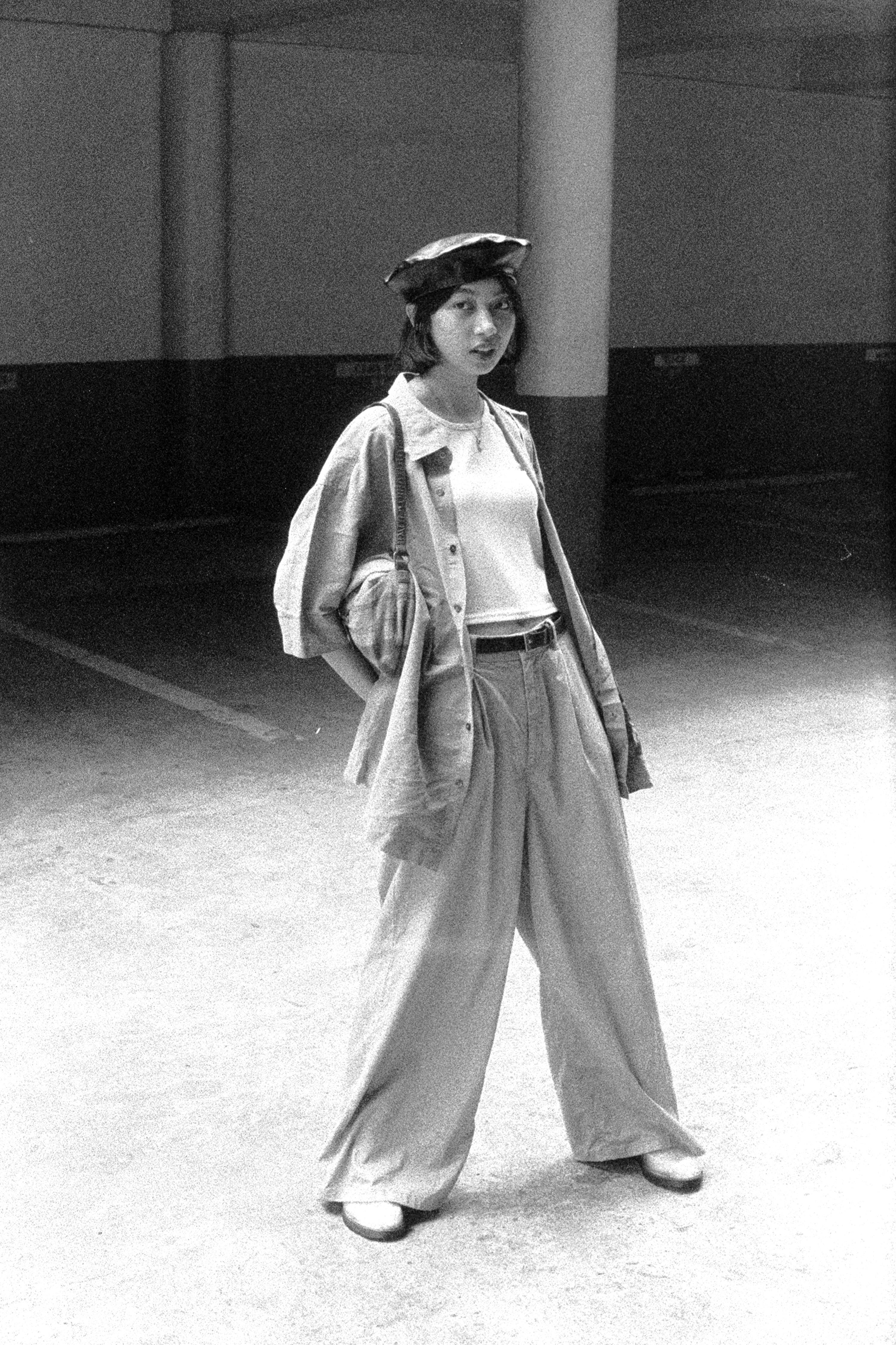 Monochrome photo of a woman in a stylish outfit standing in an industrial environment.