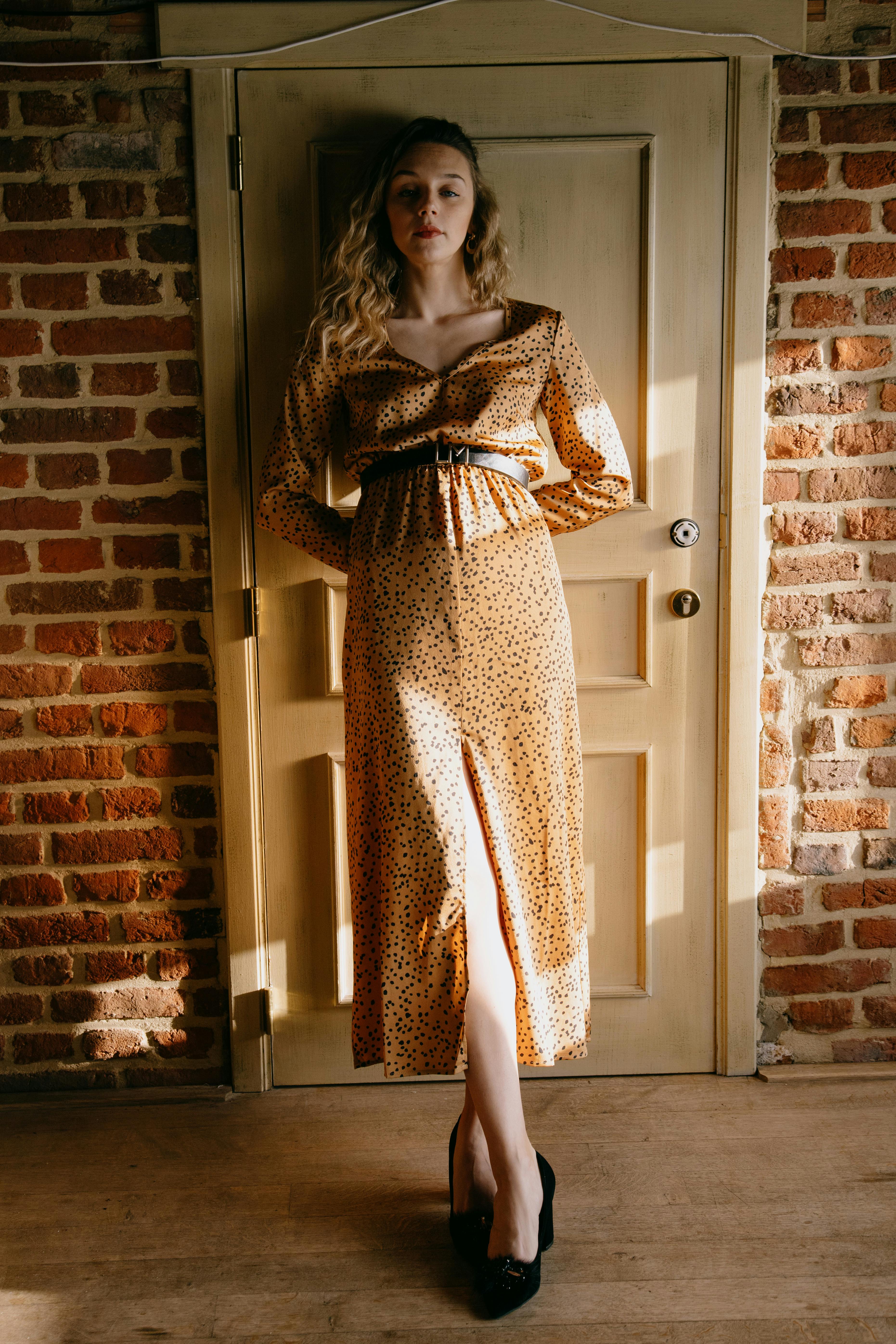 elegant dreamy woman in dress leaned on door at home