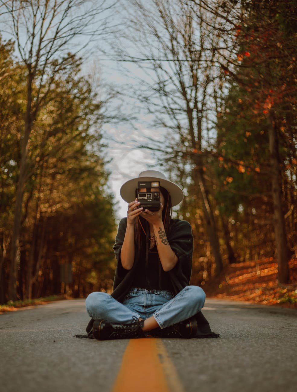 woman-holding-a-camera-sitting-in-the-middle-of-the-road-free-stock-photo