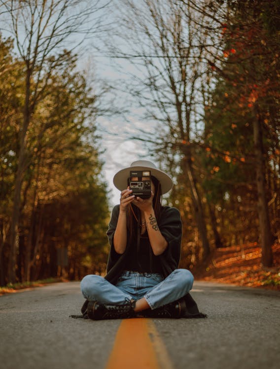 Free Woman Holding A Camera Sitting In The Middle Of The Road Stock Photo