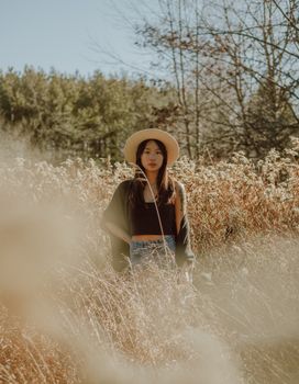 一位身着休闲装、头戴帽子的迷人冷静的亚洲女性，站在开阔葱郁的山谷中，凝视着镜头