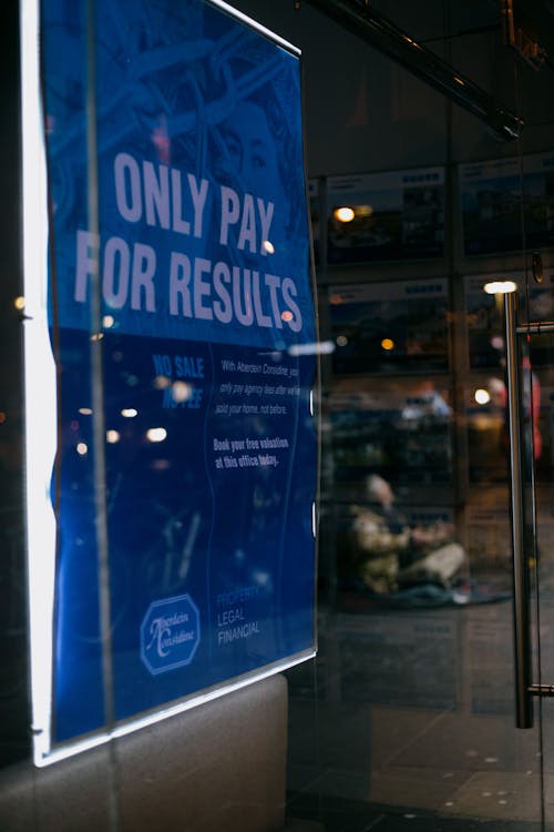 Bright advertising poster near glass wall in night city