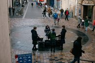 Scottish teenage musicians wearing traditional clothes and playing drums and bagpipe on street on autumn day