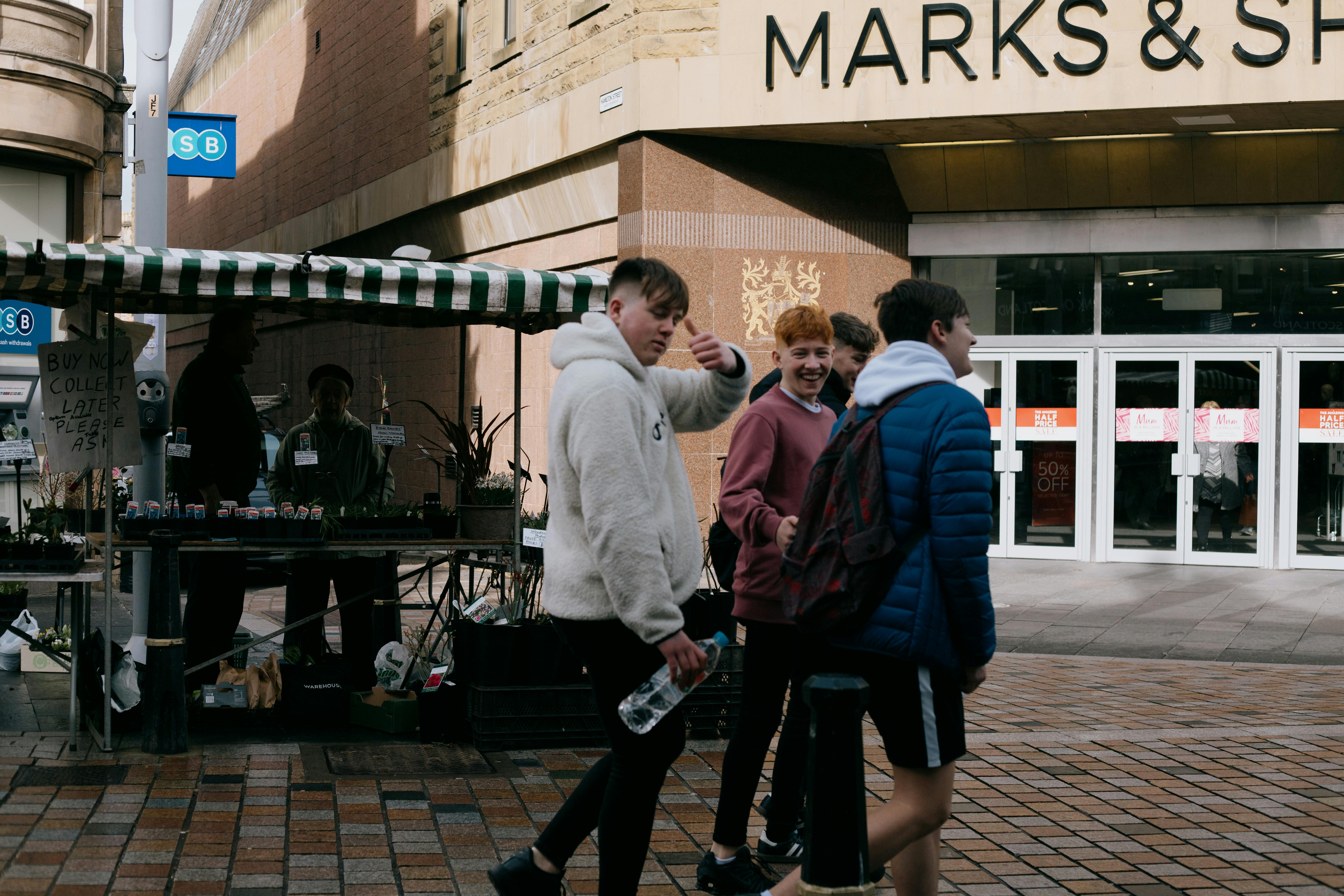 cheerful teenage boys walking on city street in autumn