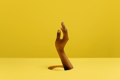 Woman Hand in Hole on Yellow Background