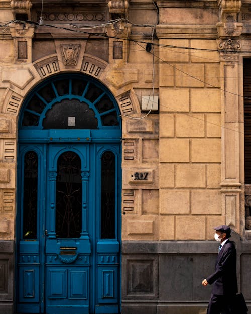 Homme En Manteau Noir Debout Devant La Porte En Bois Bleu