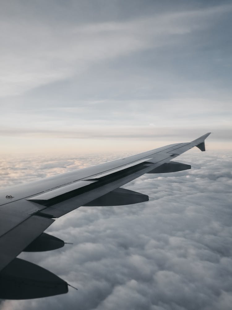 Wing Of Airplane Flying Over Clouds At Sundown