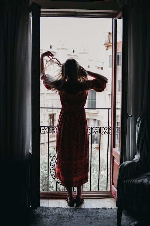 Free Unrecognizable woman touching hair and looking out balcony Stock Photo