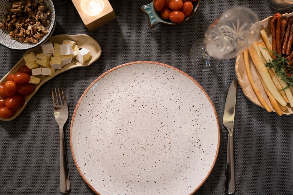 Photo by Pavel Danilyuk on Pexels Flat lay of a dinner table with an empty plate, cutlery, and various appetizers like cheese and cherry tomatoes. - Photo by Pavel Danilyuk on Pexels