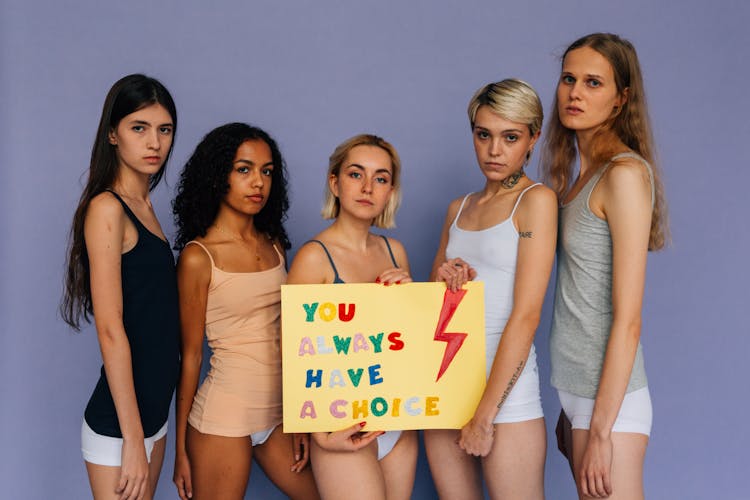 A Group Of Women Wearing Tank Tops While Holding A Banner