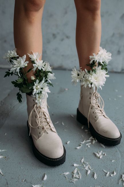White boots adorned with fresh white flowers on a textured surface, close-up view.
