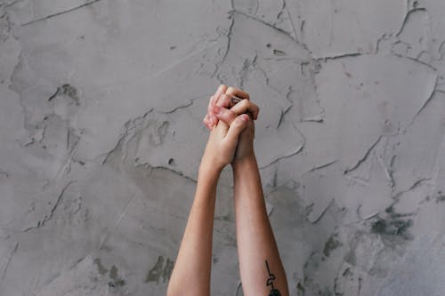 People Holding Each Others Hand Near Gray Concrete Wall