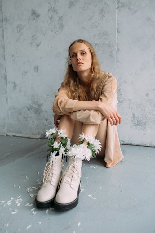 Woman in Brown Long Sleeves Sitting on the Floor while Looking at the Camera