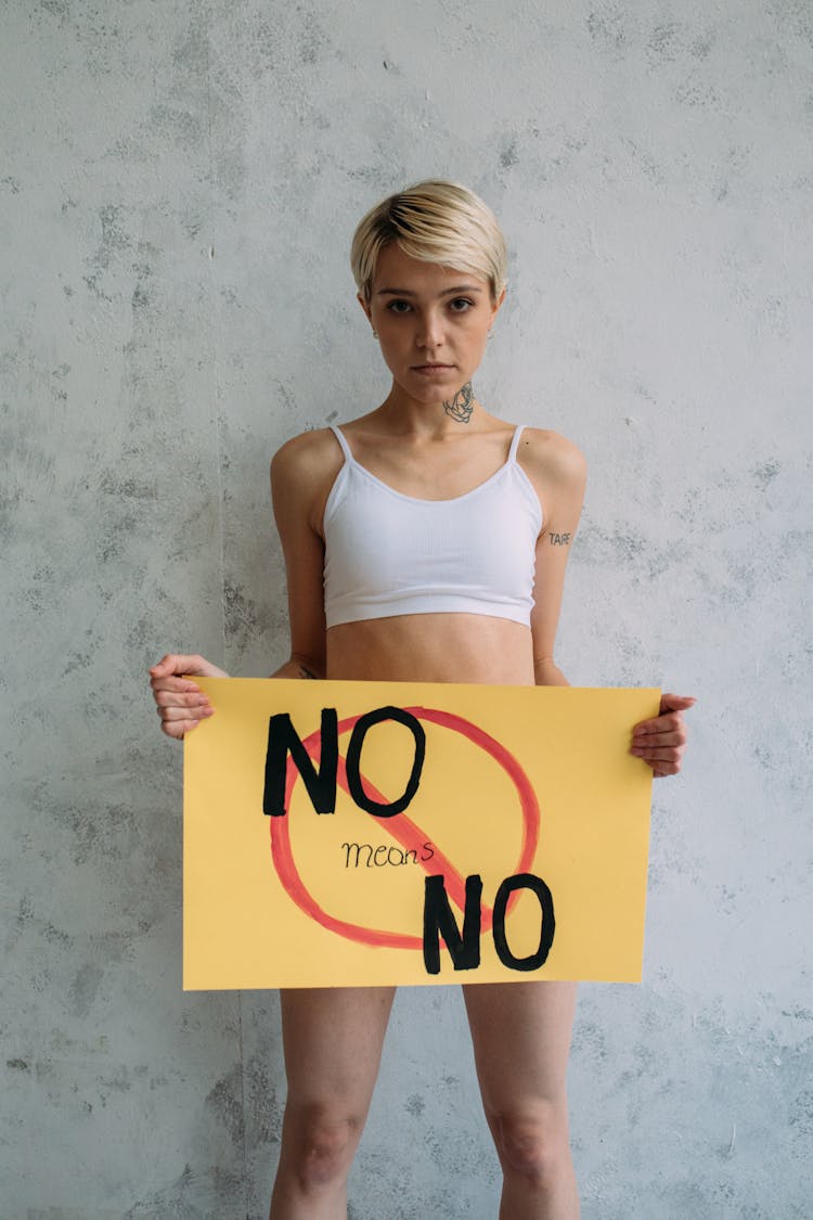 Woman In White Sports Bra Holding Banner While Looking At The Camera