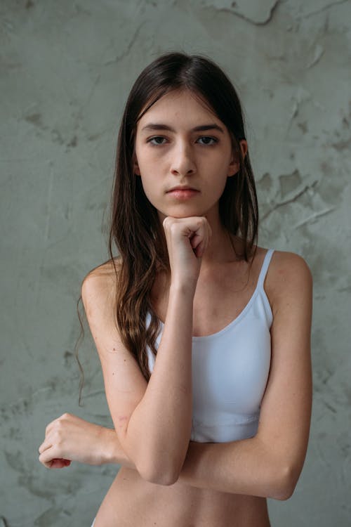 A Young Woman in White Sports Bra Looking at the Camera while Hand on Chin