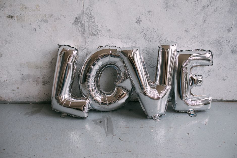 Silver letter balloons spelling 'LOVE' against a textured wall, perfect for celebrations.