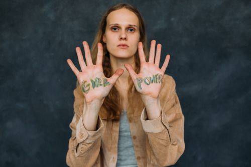 Free Portrait of a woman showing 'Girl Power' message on palms in a studio setting. Stock Photo