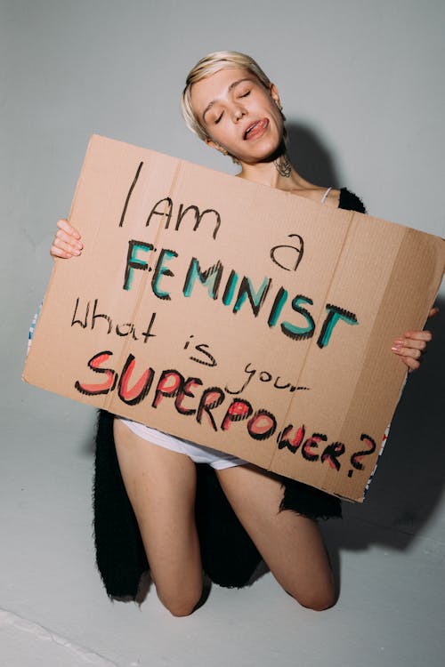 A Woman Holding a Brown Placard White Kneeling