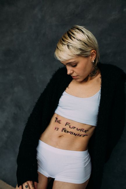 A woman with a powerful feminist message written on her body, symbolizing empowerment.