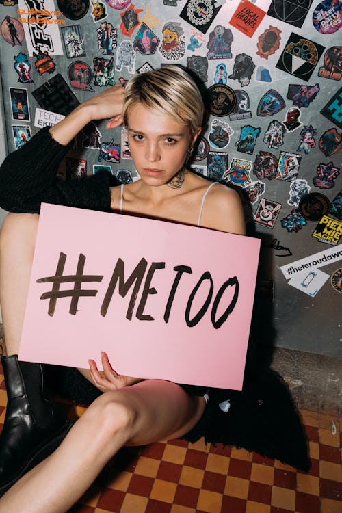 Woman Sitting on the Floor Holding a Pink Paper Placard