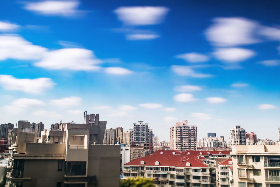 A dynamic city skyline under a vivid blue sky with scattered clouds.