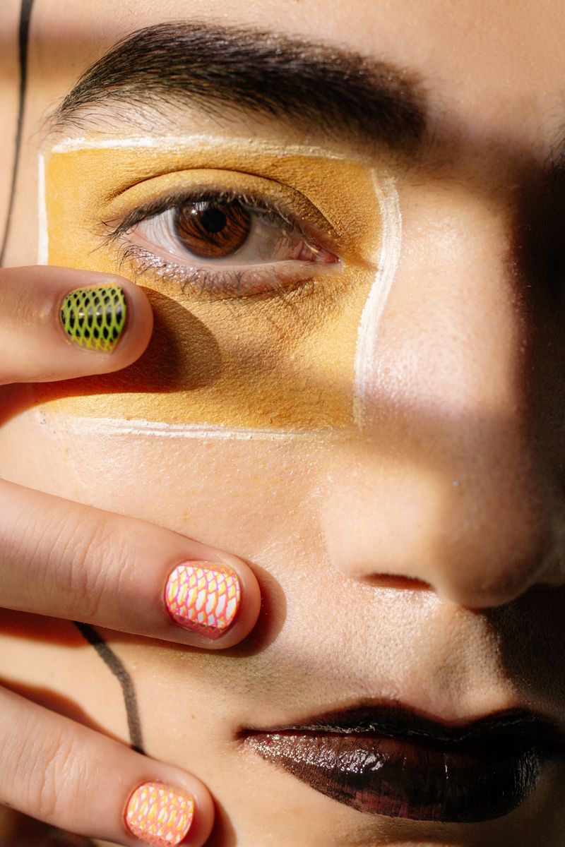 Primer plano editorial de uñas con diseño de rejilla en verde y coral