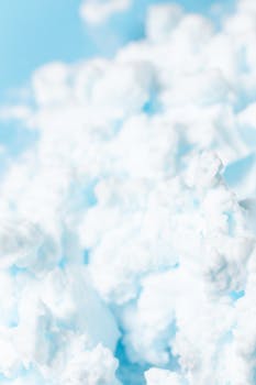 Detailed close-up image of fluffy shaving foam against a light blue backdrop, showcasing texture and softness.