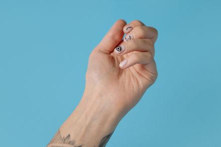 Hand with fine-line nail art on a pale blue backdrop — photo by cottonbro studio on Pexels