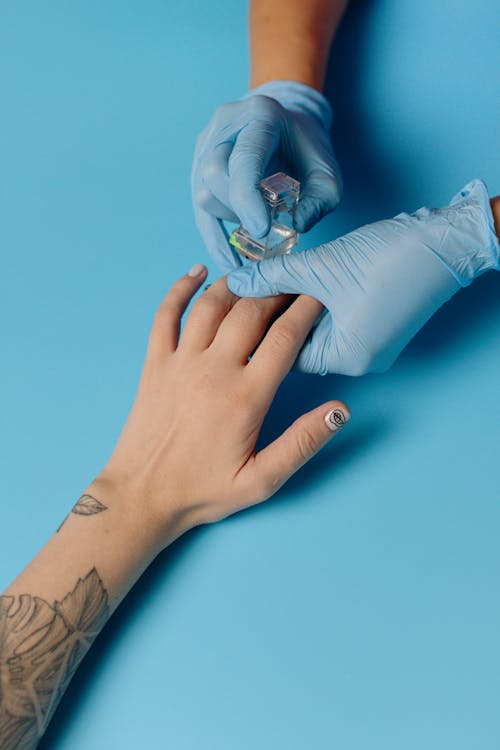 Person With Blue Gloves Applying Nail Polish 