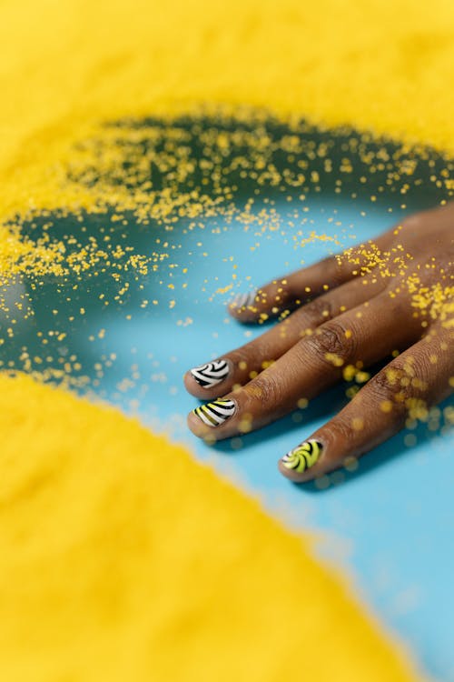 Pessoa Com Manicure Azul Em Tecido Amarelo E Azul