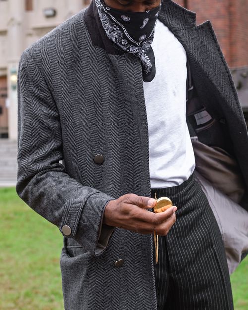 Free A stylish man in a gray coat checks his pocket watch outdoors, exuding elegance. Stock Photo