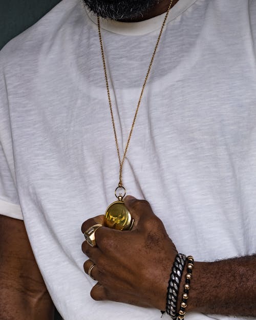 Free Close-Up Shot of a Person in White Shirt Holding a Gold a Necklace Stock Photo