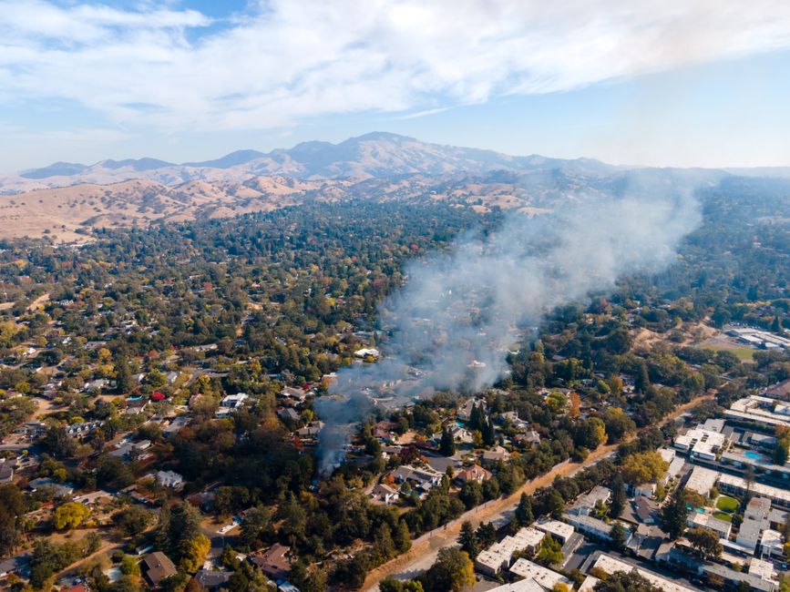 Aerial view of Walnut Creek, CA, showing smoke rising from residential area near Mount Diablo.