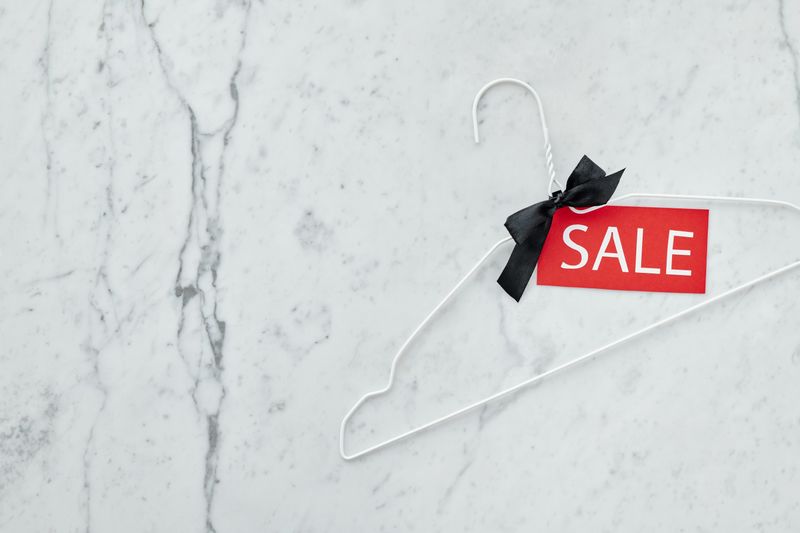 White clothes hanger with sale tag on marble background. Perfect for retail promotions.