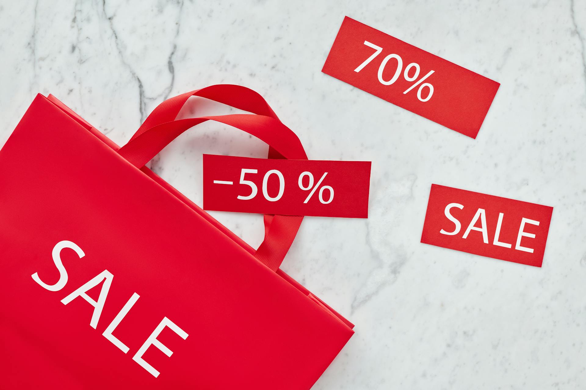 Red shopping bag and discount cards with percentages for promotional sale.