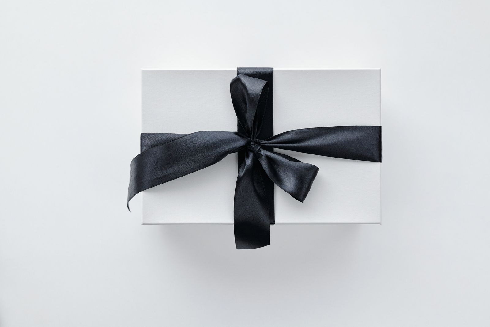 A white gift box tied with a black satin ribbon