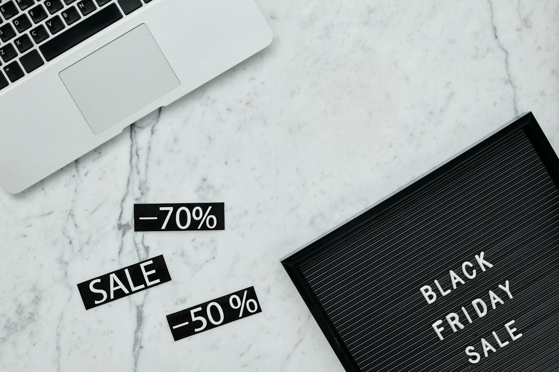 Stylish flat lay showcasing Black Friday sale with discounts on a marble surface.