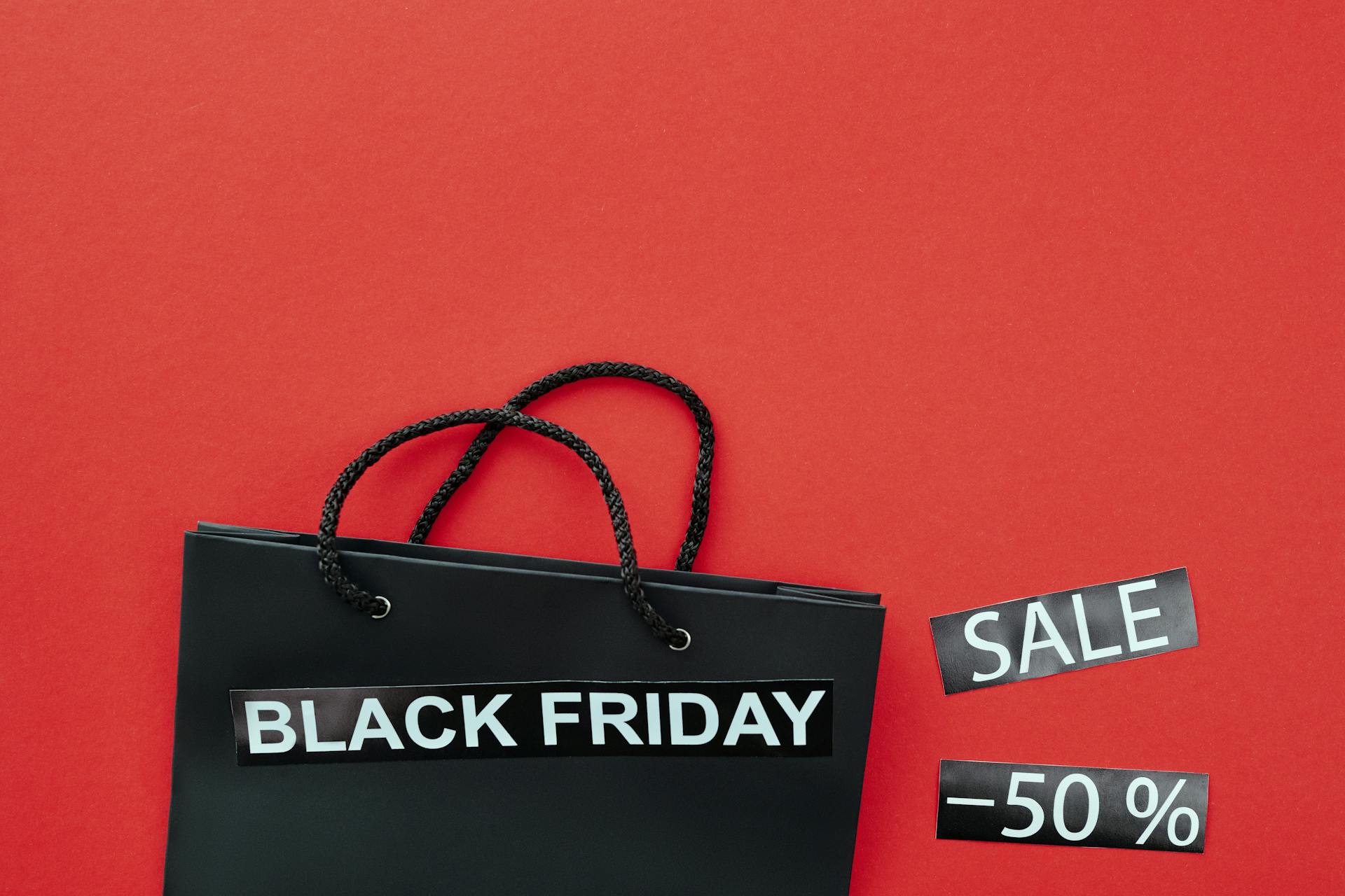 Close-Up Shot of a Black Shopping Bag beside Discount Tags