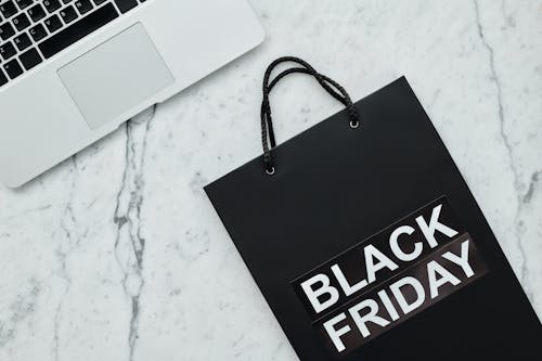 Free Close-Up Shot of a Laptop beside a Black Shopping Bag Stock Photo