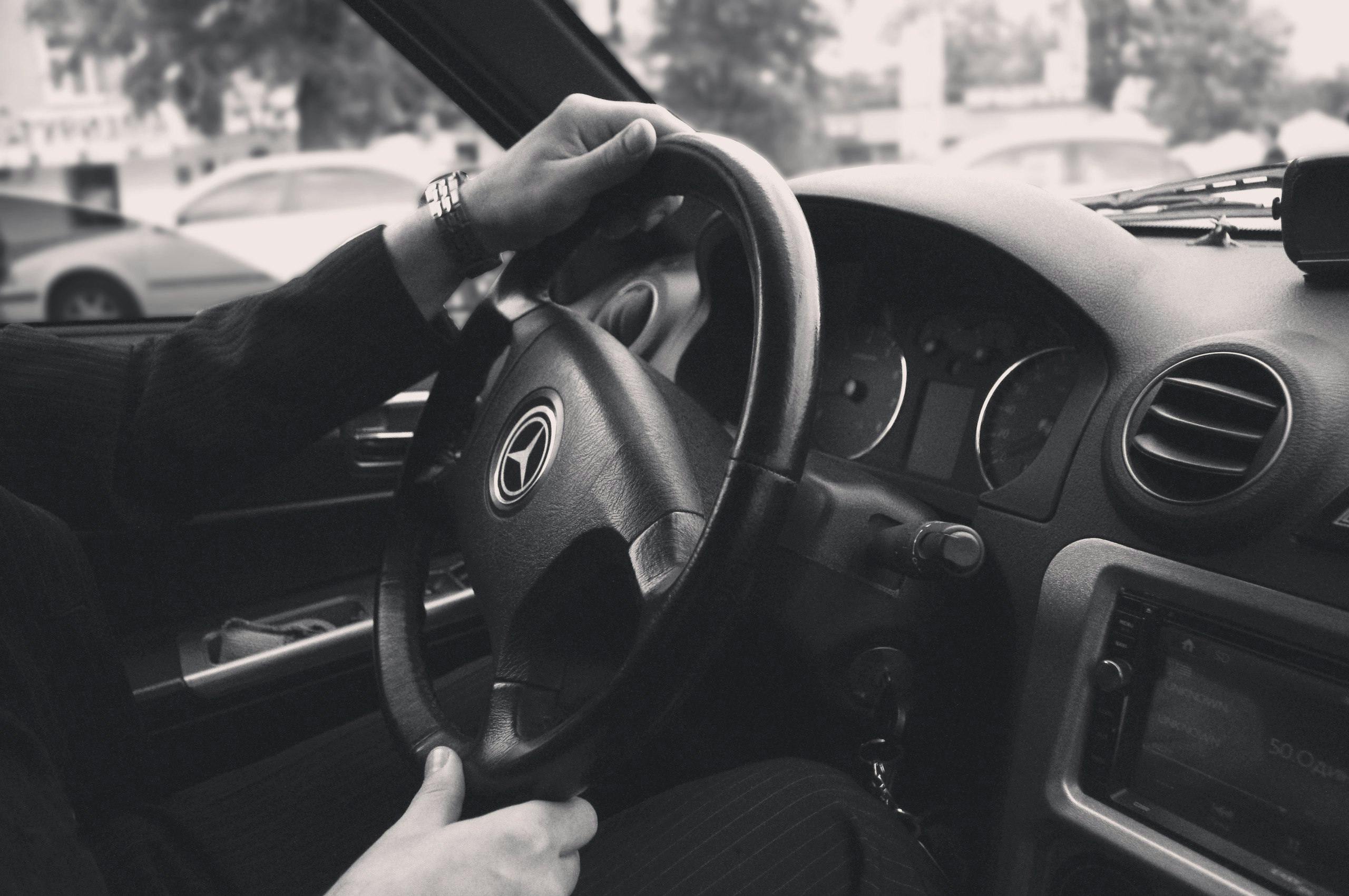 grayscale photography of person driving a car