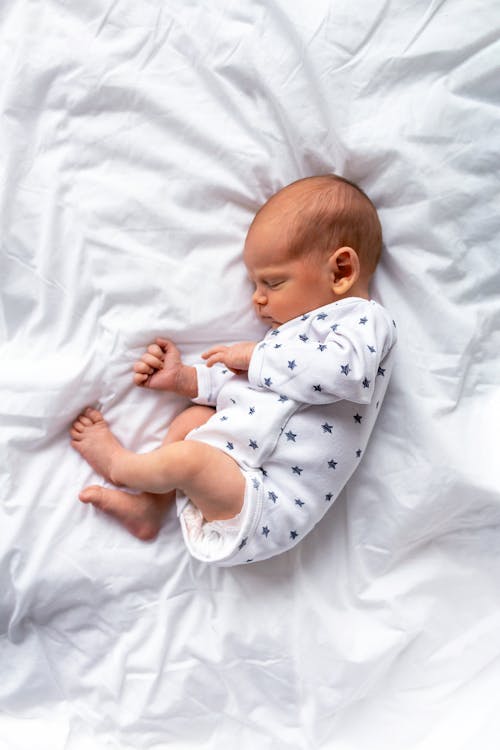 Free A Baby in White Onesie Sleeping on the Bed Stock Photo