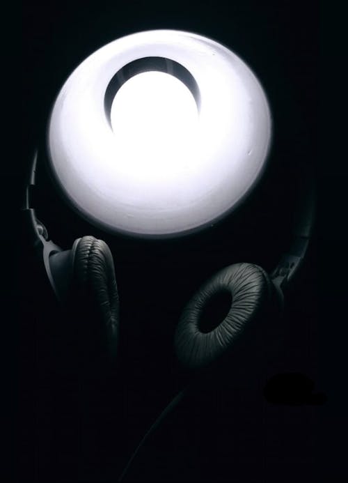 Close-Up Shot of Black Headphones beside a Desk Lamp