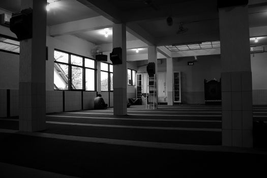 A serene black and white view of an empty hallway featuring pillars and windows, capturing urban tranquility.