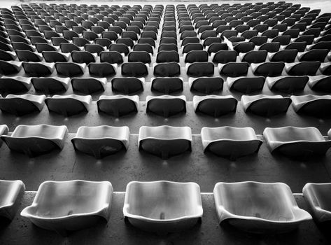 A black-and-white image of empty rows of stadium seats, creating a striking pattern.