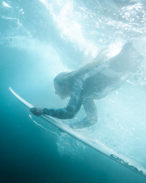 Underwater Photography of Woman Holding a Surfboard