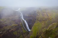 在多雾的冰岛风景中，令人惊叹的瀑布穿过岩石悬崖