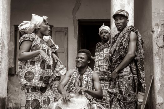 Group of adults in traditional Ghanaian attire, engaging in cultural activities.