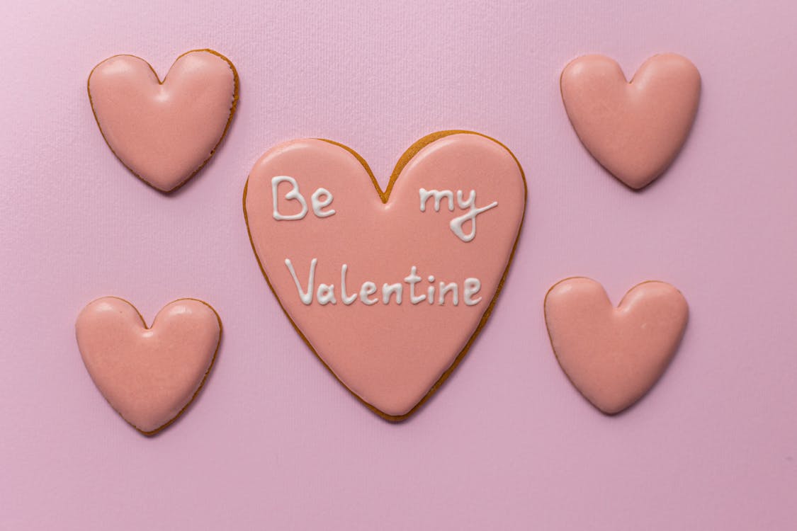 Free Top view of sweet heart shaped cookies saying Be My Valentine on pink background Stock Photo