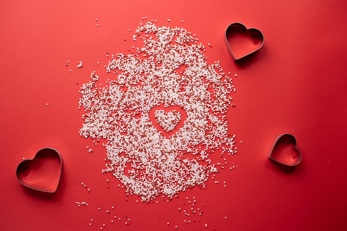 Free Top view of hearts shape in form for cooking near sprinkling on red background Stock Photo