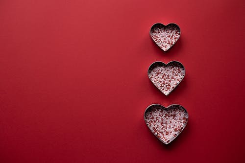 Top view of different hearts forms for cooking with sprinkling on red background